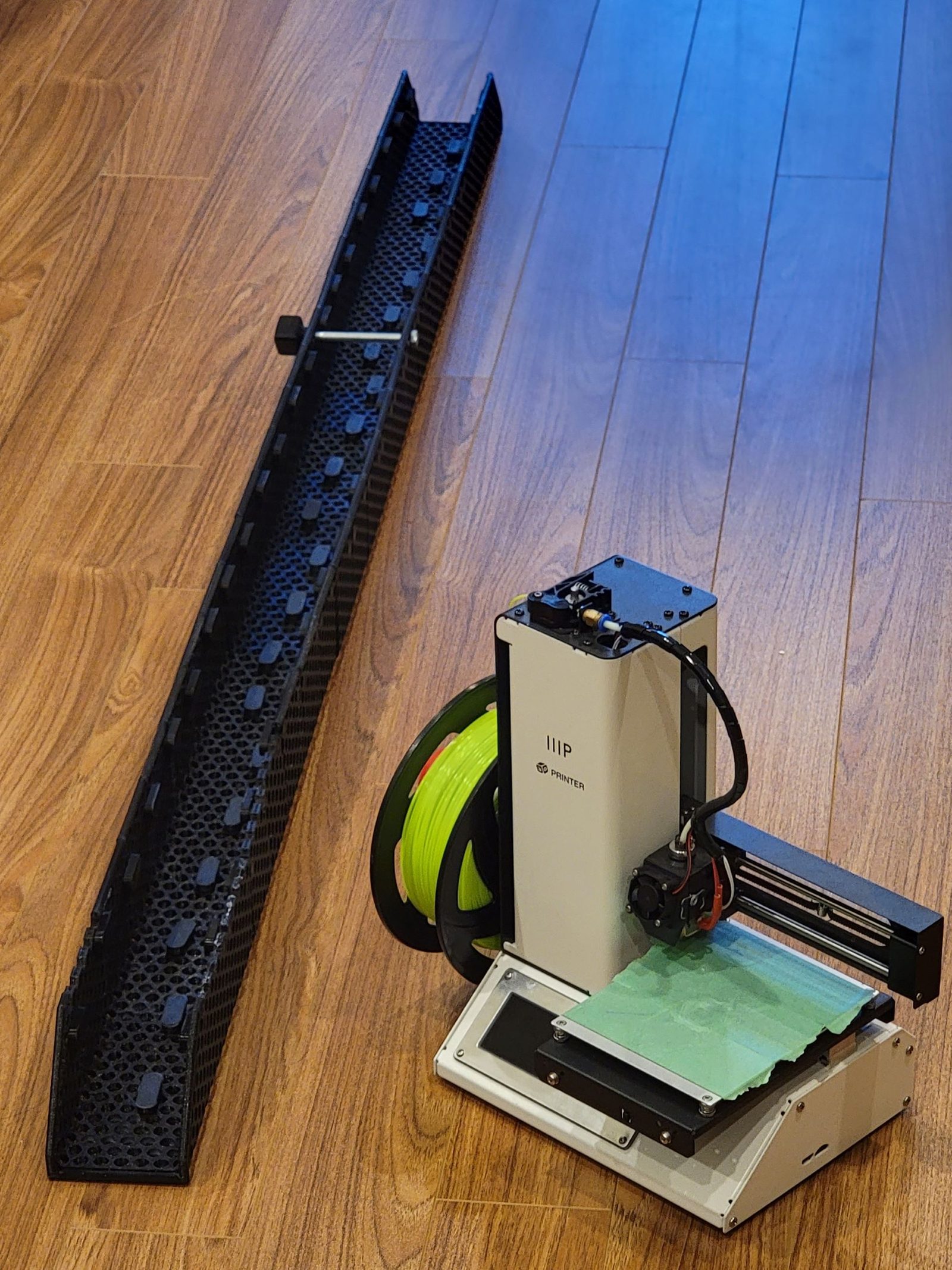 A 3D printer mid-print on a hardwood floor