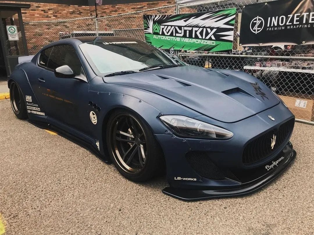 A wide-body Maserati GranTurismo MC with bronze wheels at a car show