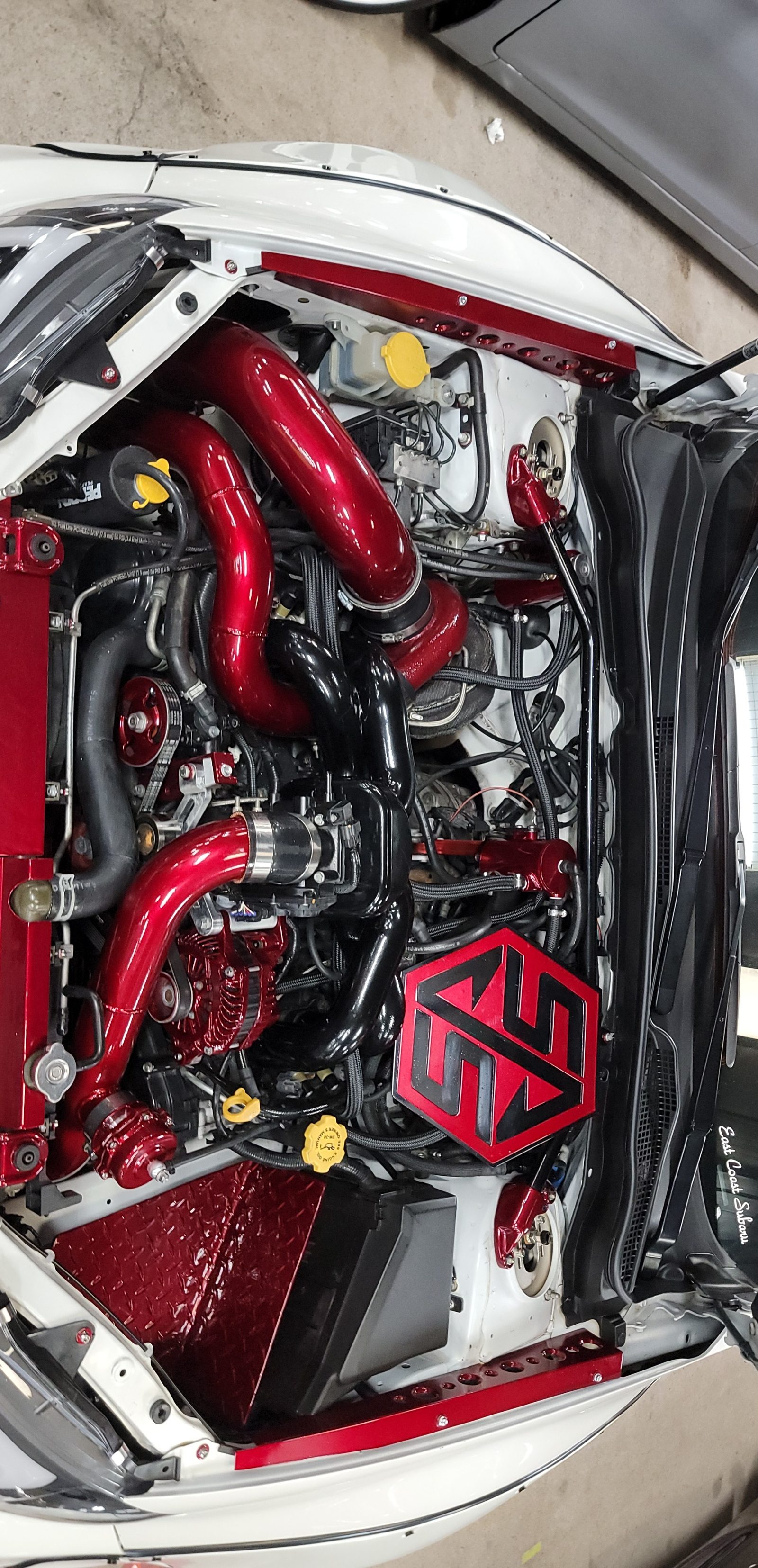 A spotless tuned Subaru engine bay with red and black piping