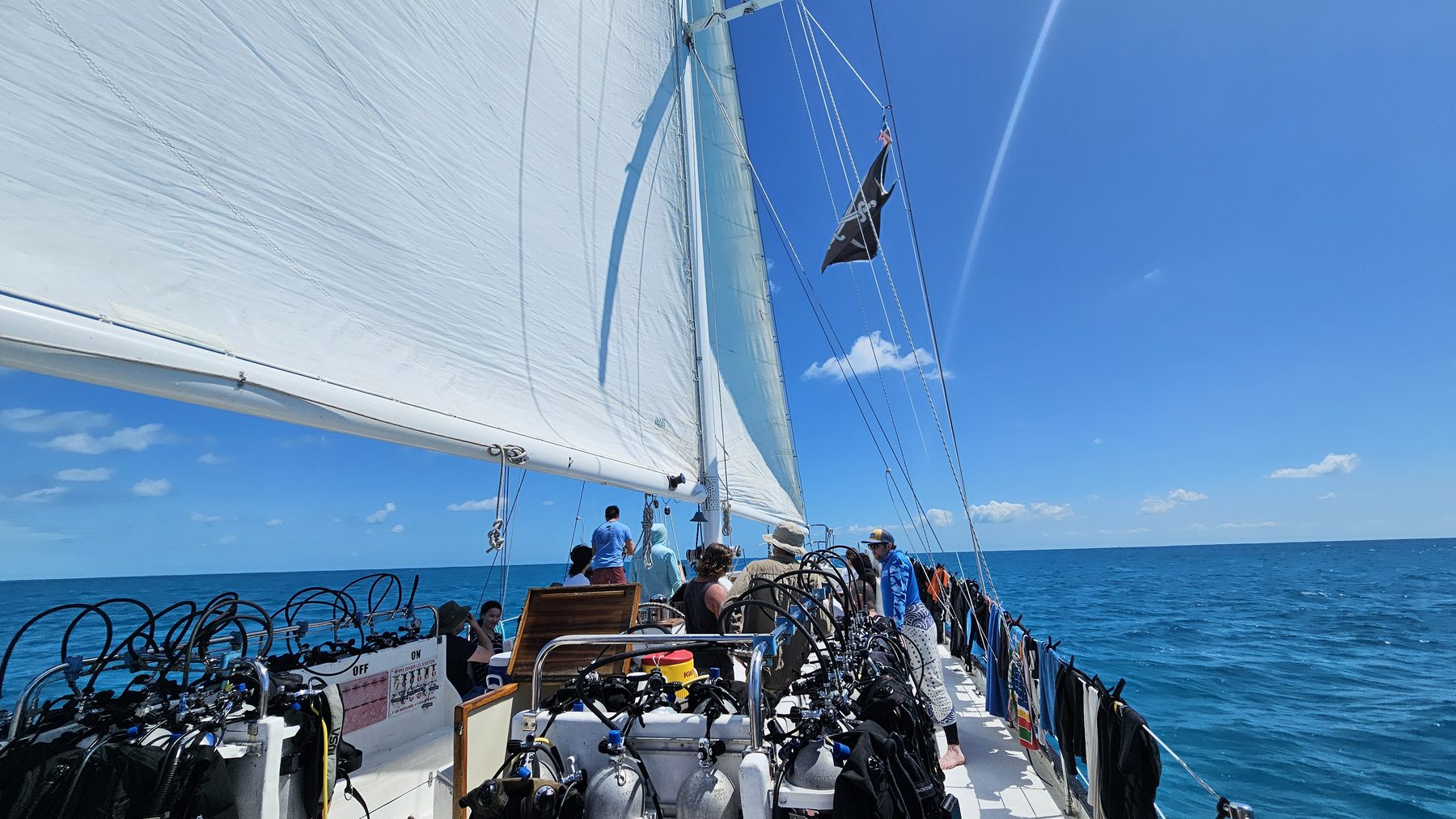 A sailboat under full sail in the Bahamas with the pirate flag flying