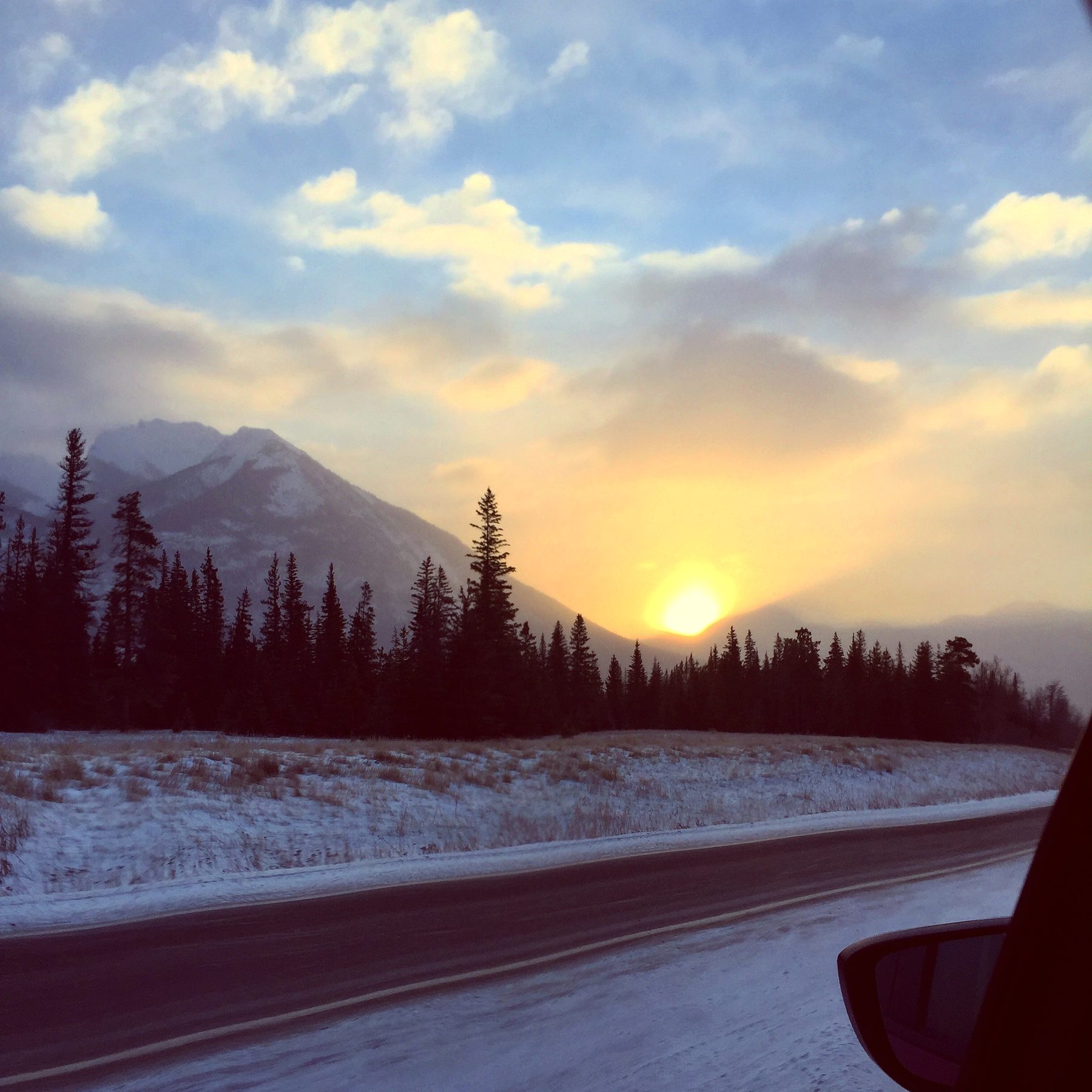 A winter sunset over a snowy road through the Rockies