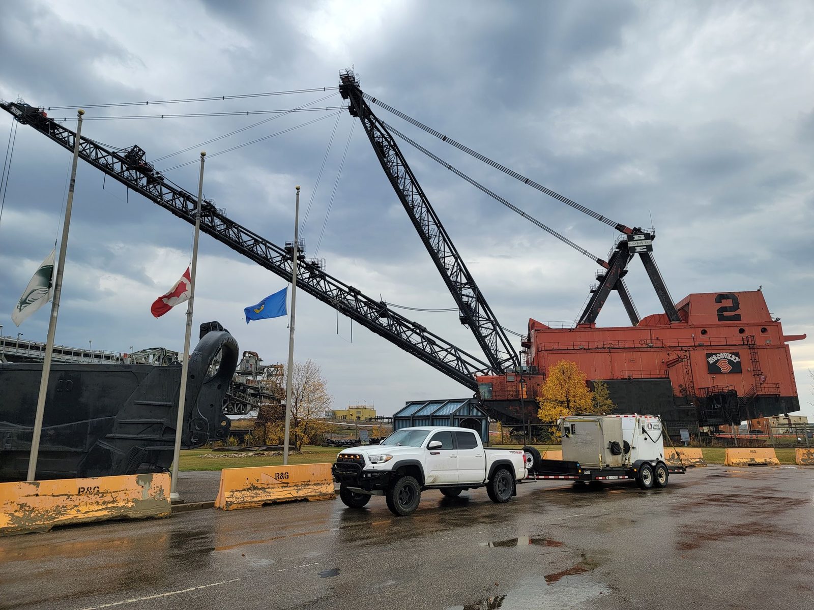 A Toyota Tacoma towing a piece of survey equipment past the Diplomat Mine dragline display in Forestburg, Alberta