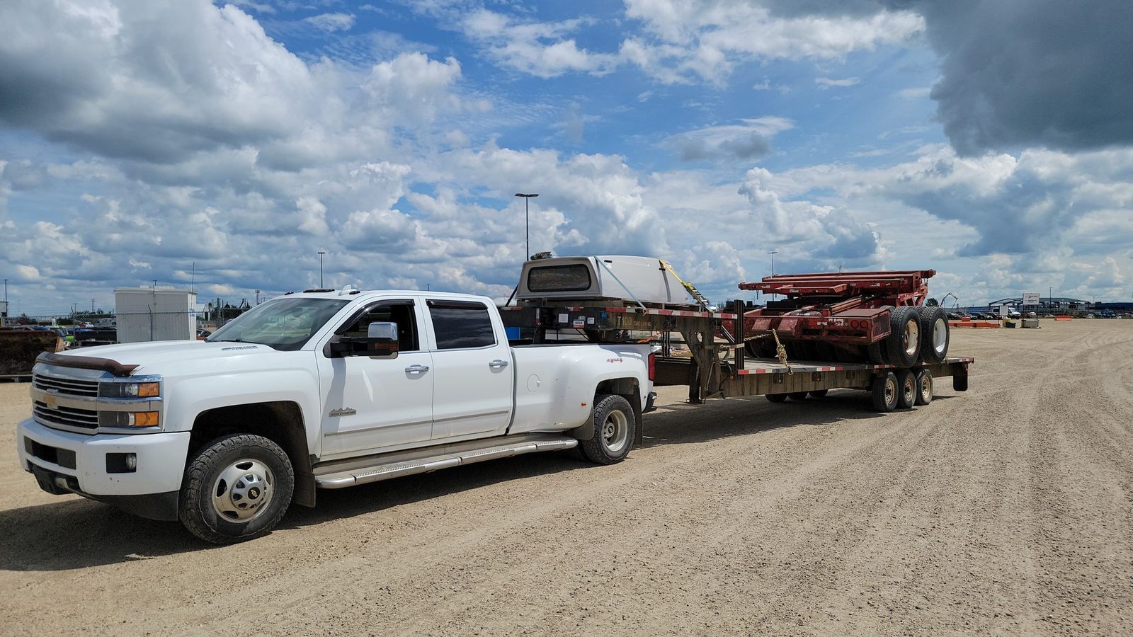 A heavy-duty pickup with a flatbed trailer at a yard
