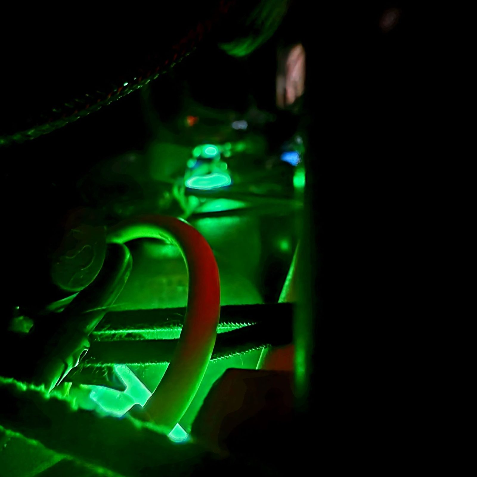 An abstract green-lit close-up of marine equipment at night