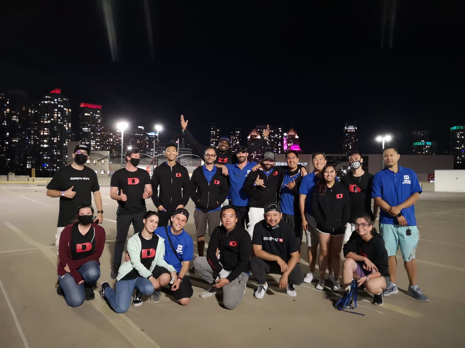 The Driven Aftermarket team posing at night with a city skyline behind them